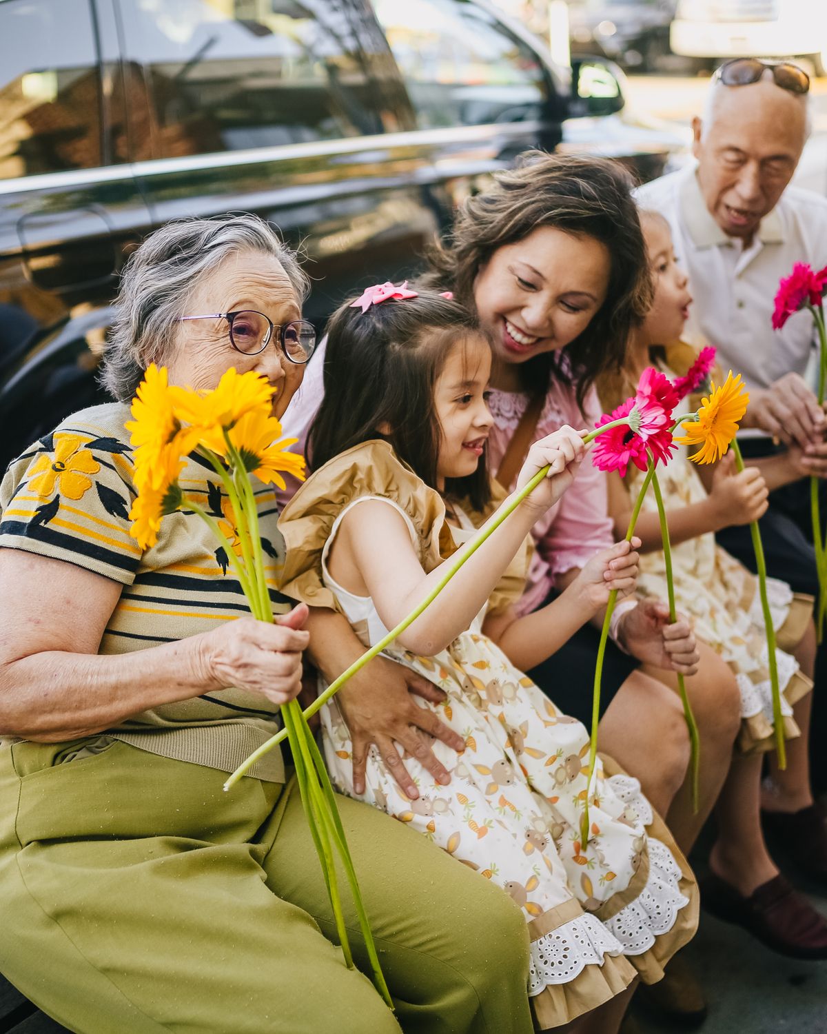 Three generations of a family laughing together with flowers