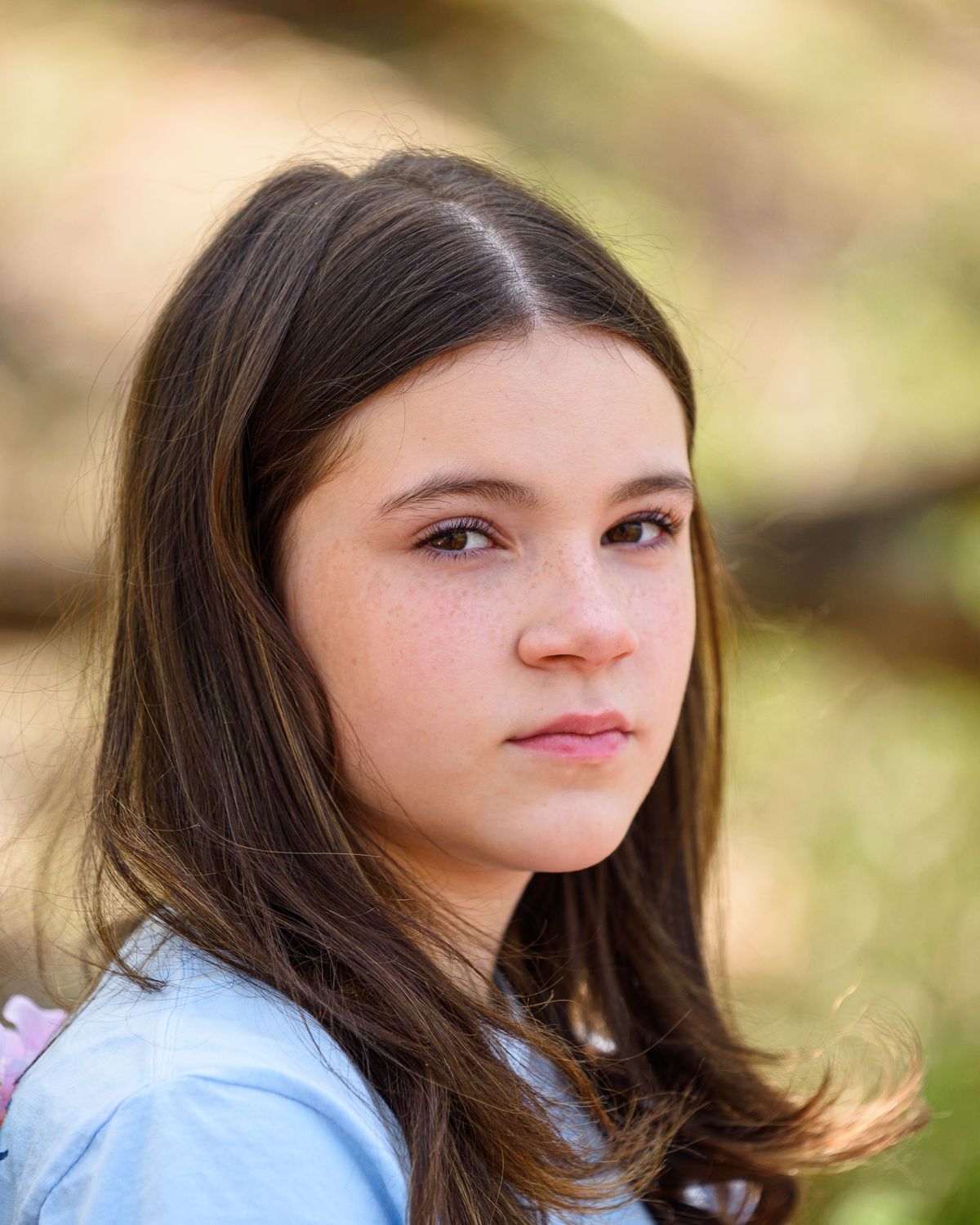 A teenager outdoors in soft natural light, looking thoughtful