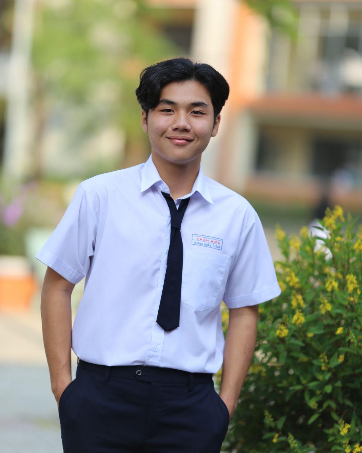 A teenage boy in school uniform smiling outdoors